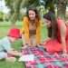 A child and two women enjoying a drawing session on a picnic blanket in a park in Portugal.